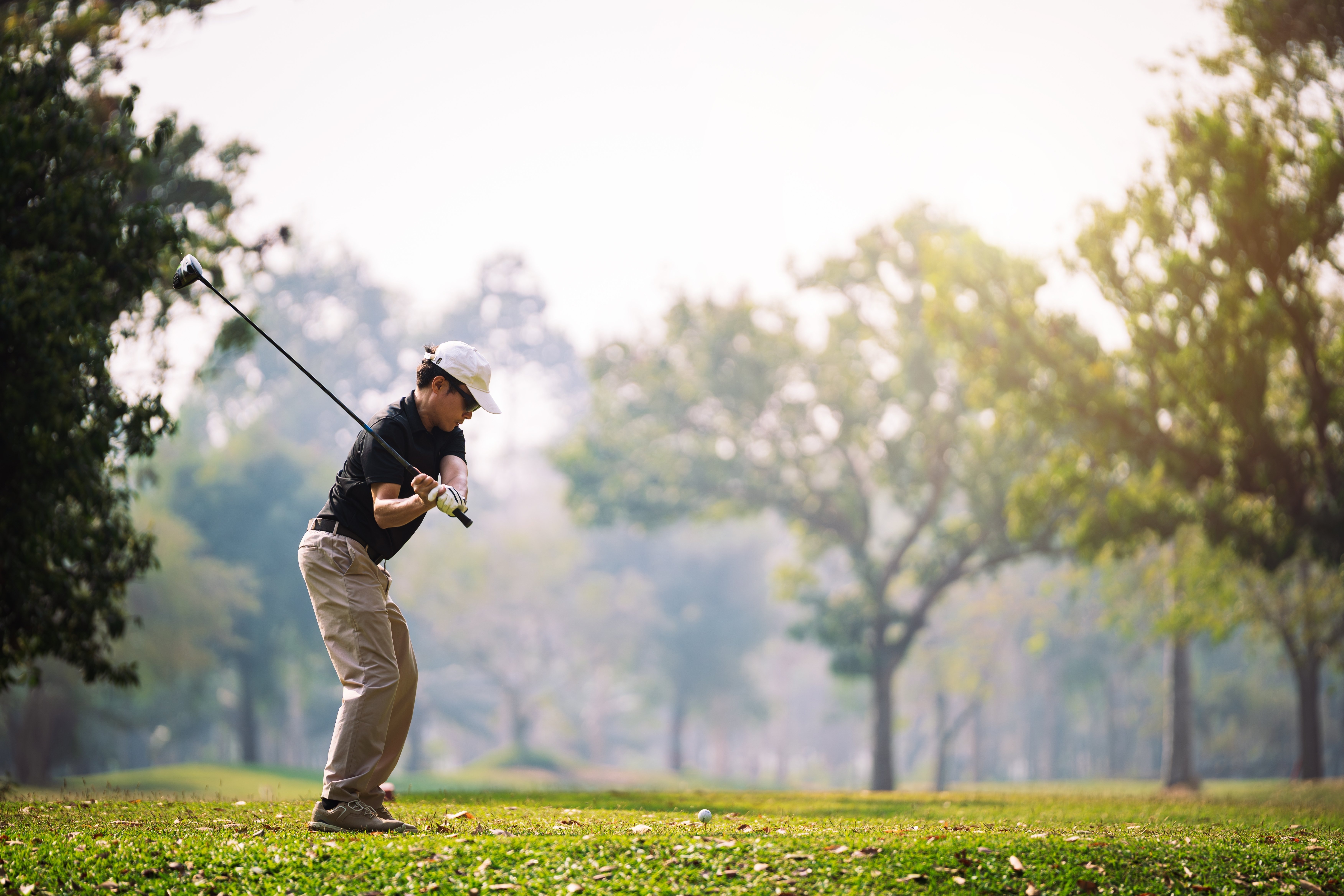 Hombre golfista prepara su swing en un campo de golf con árboles